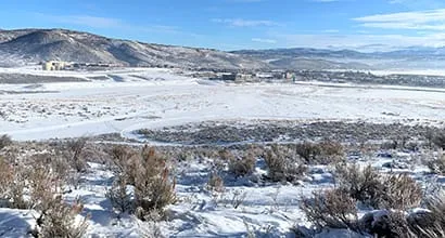 Snow-covered landscape with mountains and buildings in the distance.