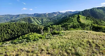 Panoramic view of a green mountainous landscape under a blue sky with few clouds.