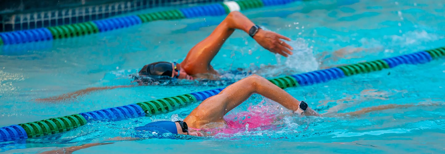 Two people swimming in a pool, each in their own lane