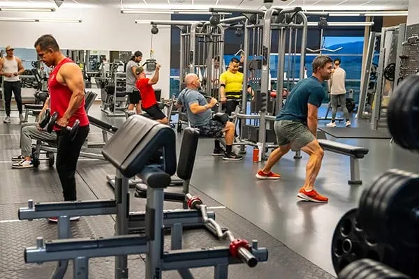 People working out in a gym with various exercise machines and weights.