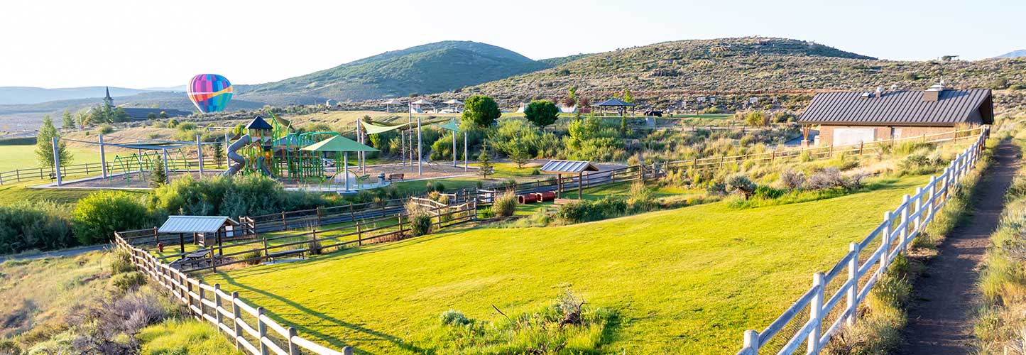 Park with playground, hot air balloon, and surrounding hills.