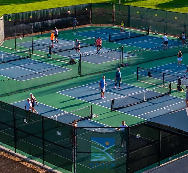 An ariel view of tennis courts, with people playing tennis on them.